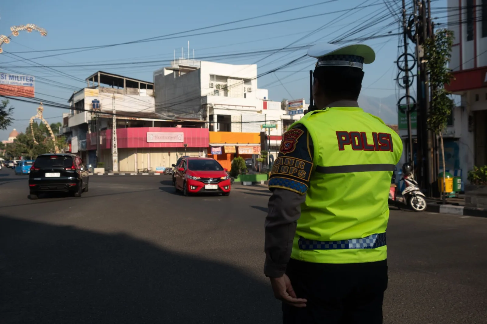 Un agente de tránsito dirige los autos en una calle soleada de Garut, Indonesia.
