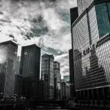 Chicago cityscape featuring Trump Tower with dramatic reflections against a cloudy sky.
