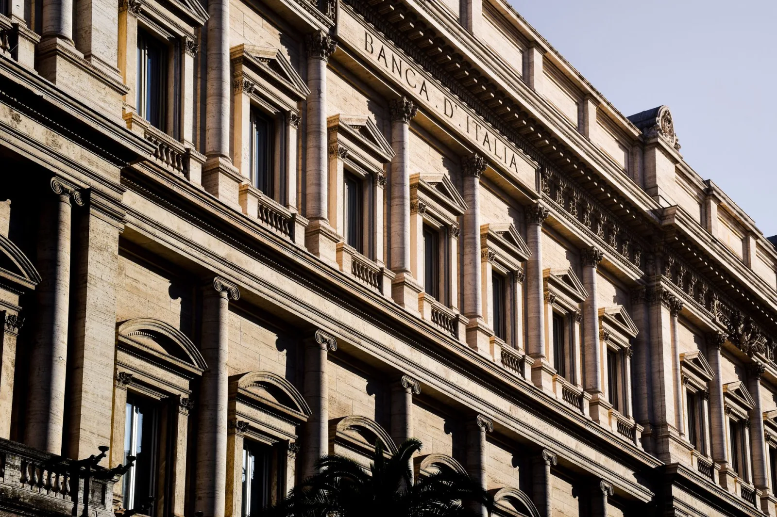 Fachada iluminada por el sol de la icónica Banca d'Italia en Roma, que destaca su arquitectura clásica.