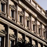 Fachada iluminada por el sol de la icónica Banca d'Italia en Roma, que destaca su arquitectura clásica.