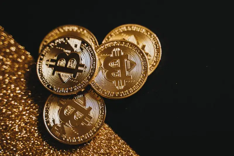 A detailed close-up shot of shiny bitcoin coins resting on a glittery surface, symbolizing wealth in digital currency.