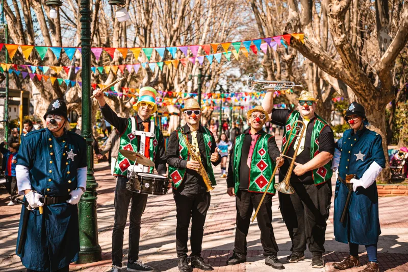 Vibrante banda de calle actuando con trajes festivos durante un festival al aire libre en un día soleado.
