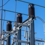 Detailed view of electrical components in a power substation under a clear blue sky.