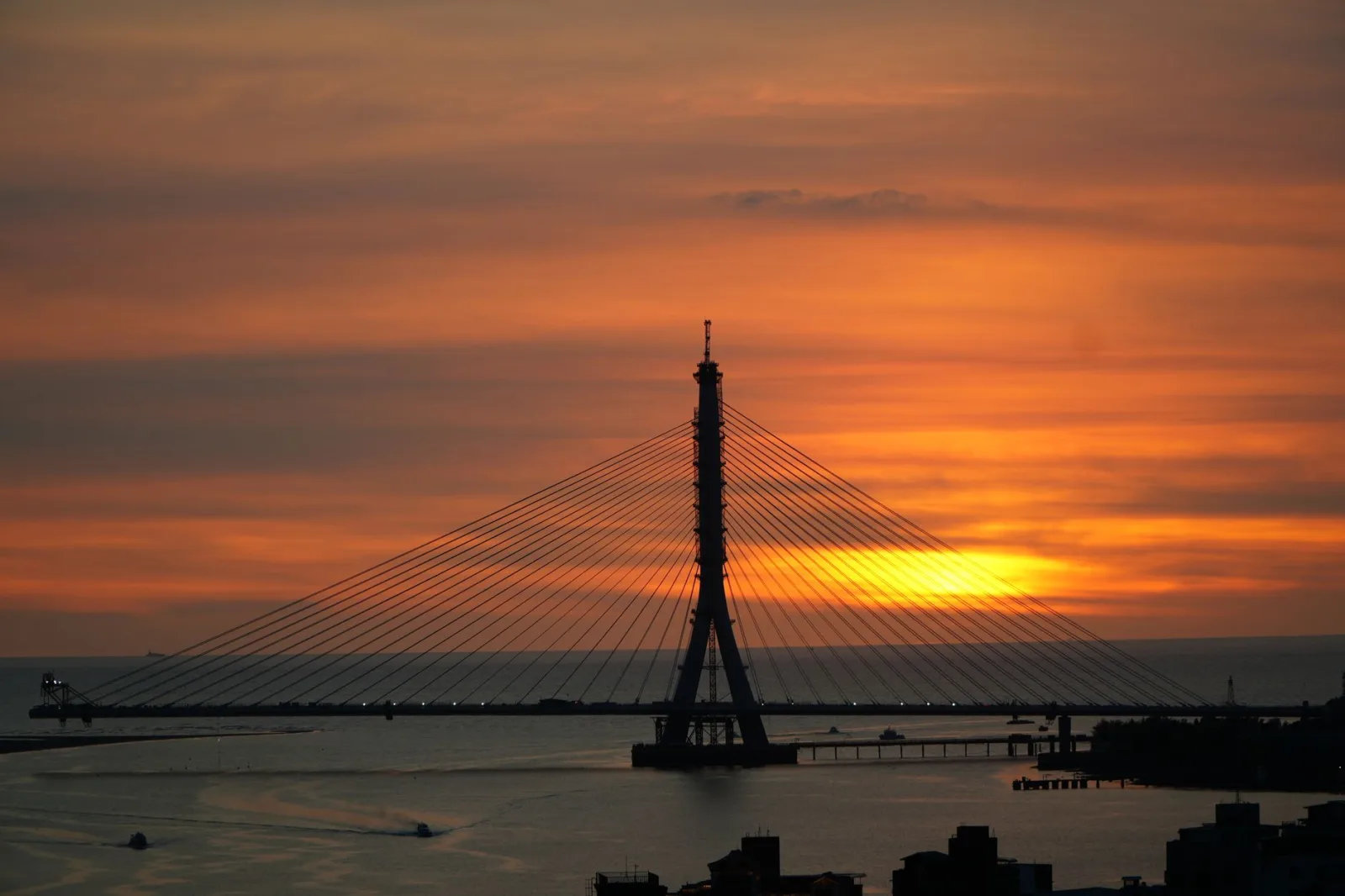 Una hermosa puesta de sol detrás del puente del río Tamsui, en Nuevo Taipéi, Taiwán, con cálidos tonos anaranjados.