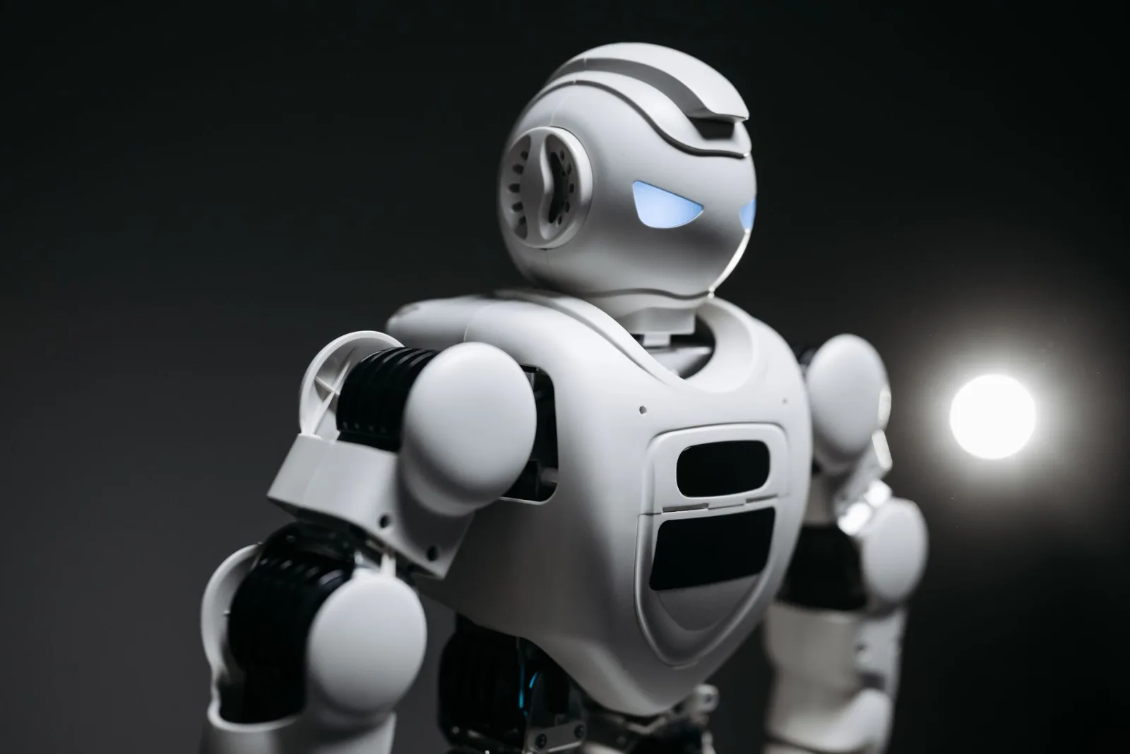 Imagen de primer plano con gran nivel de detalle de un robot blanco con ojos brillantes, iluminado en un estudio. Innovación tecnológica moderna.