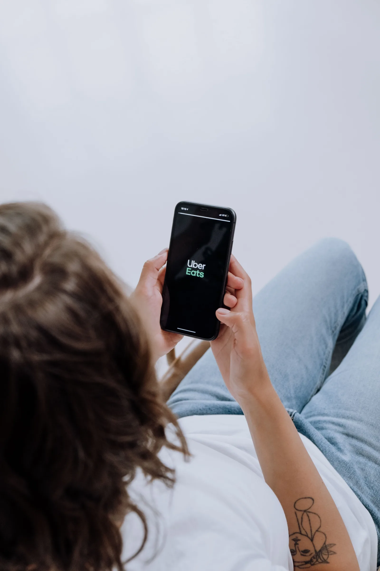 Vista desde arriba de una persona usando la aplicación Uber Eats en un teléfono inteligente, que muestra la integración de tecnología moderna.