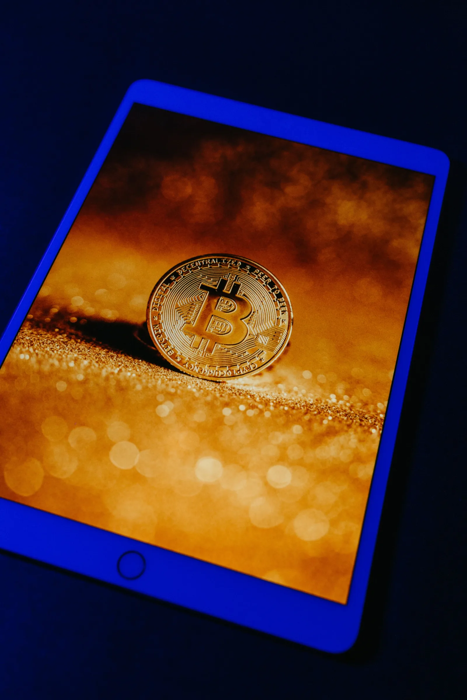 Una moneda dorada de Bitcoin mostrada digitalmente en la pantalla de una tableta, que representa la moneda digital y la tecnología blockchain.