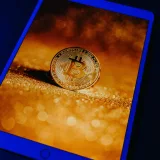 Una moneda dorada de Bitcoin mostrada digitalmente en la pantalla de una tableta, que representa la moneda digital y la tecnología blockchain.