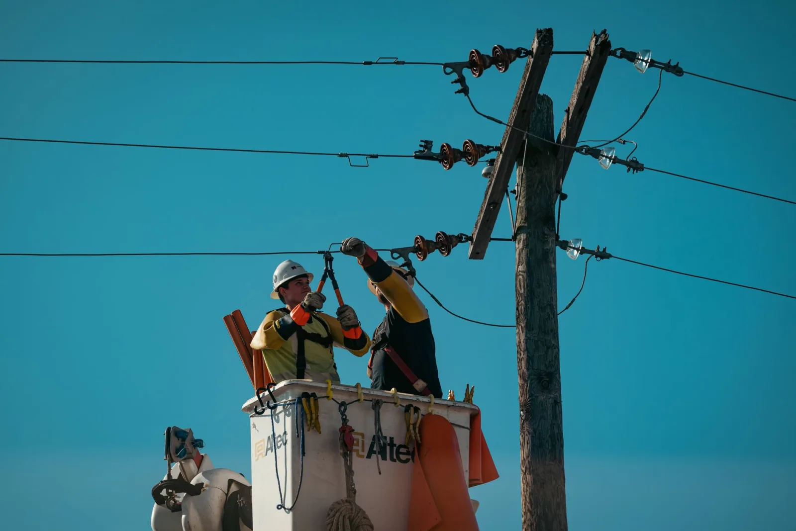 Electricistas con equipo de seguridad trabajando en líneas eléctricas a plena luz del día. Enfoque en la industria energética.