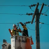 Electricistas con equipo de seguridad trabajando en líneas eléctricas a plena luz del día. Enfoque en la industria energética.