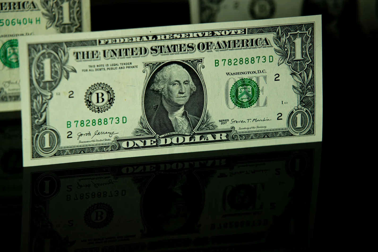 Primer plano detallado de un billete de un dólar estadounidense con reflejo, que destaca el diseño de la moneda.