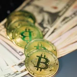 Close-up of gold bitcoins and US dollar bills representing cryptocurrency and digital wealth.