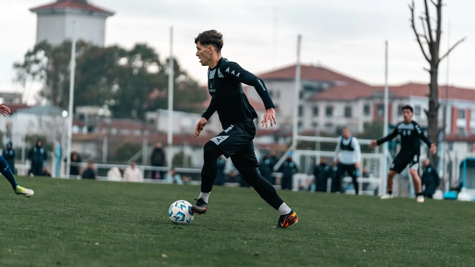 Joven futbolista talentoso regateando durante un partido en un día soleado.