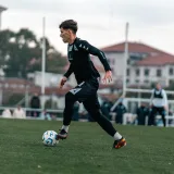 Joven futbolista talentoso regateando durante un partido en un día soleado.