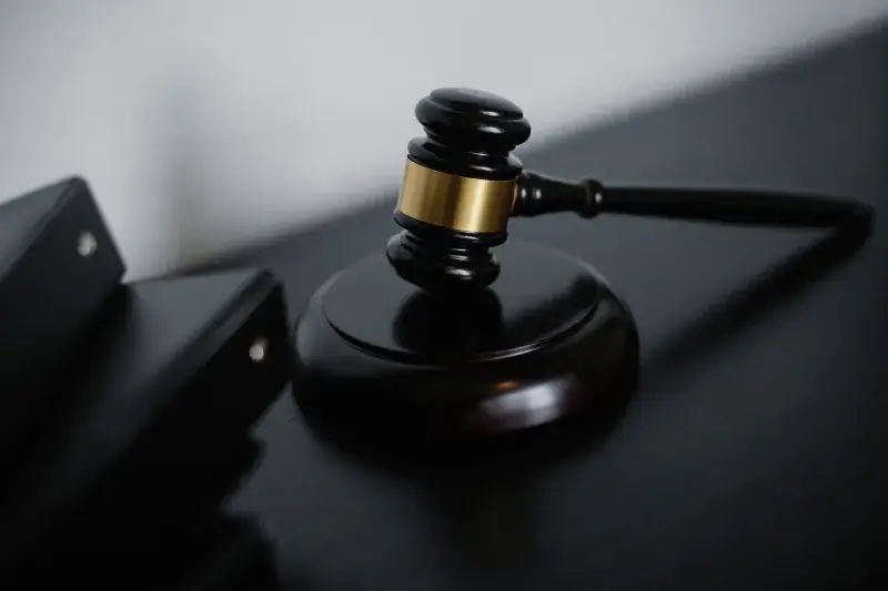High angle of shiny wooden ceremonial mallet with golden detail placed on judge tale near documents folders