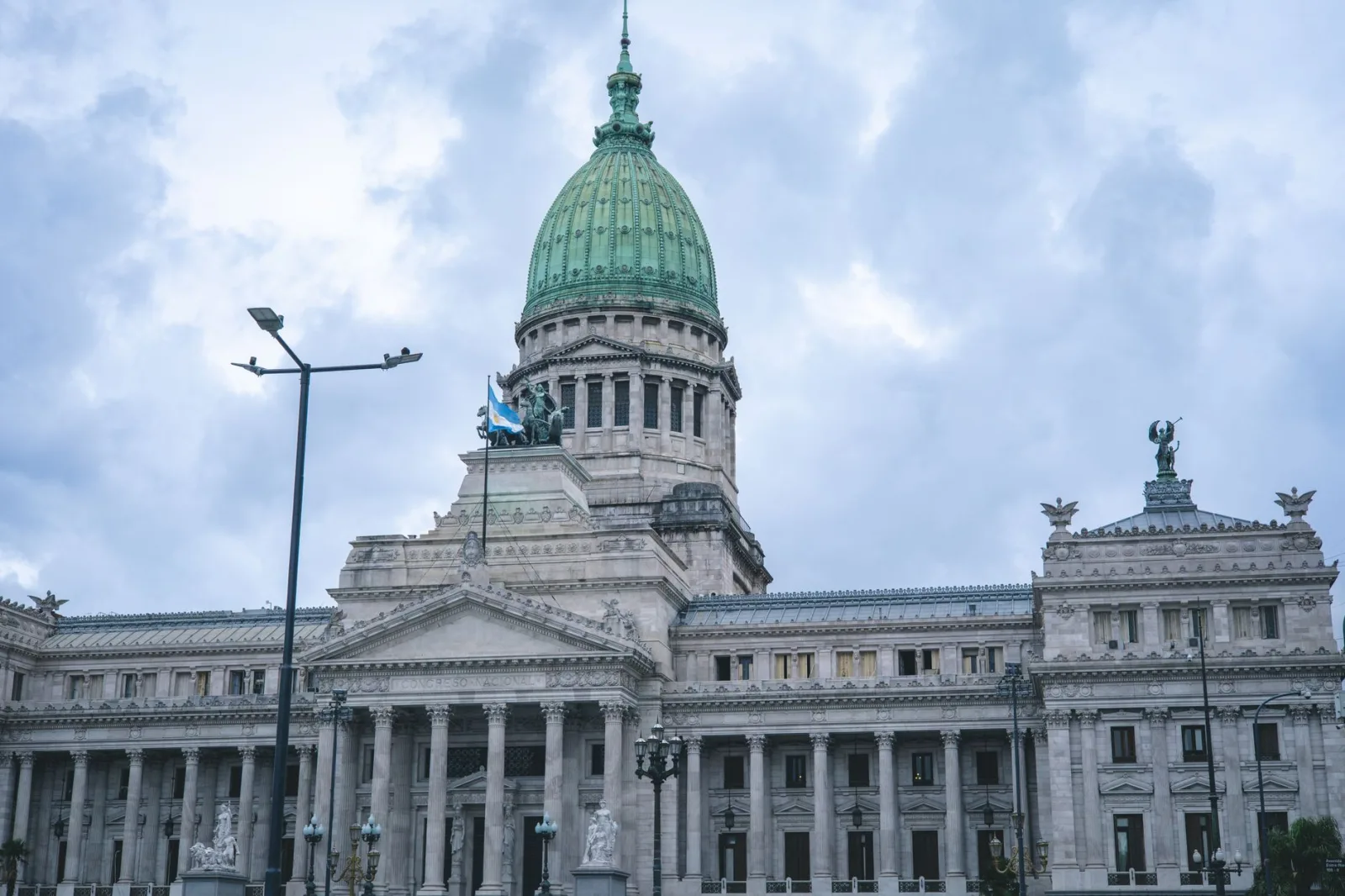 Vista desde abajo del icónico edificio del Congreso Nacional en Buenos Aires, con cielo nublado.