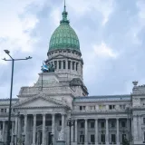 Vista desde abajo del icónico edificio del Congreso Nacional en Buenos Aires, con cielo nublado.