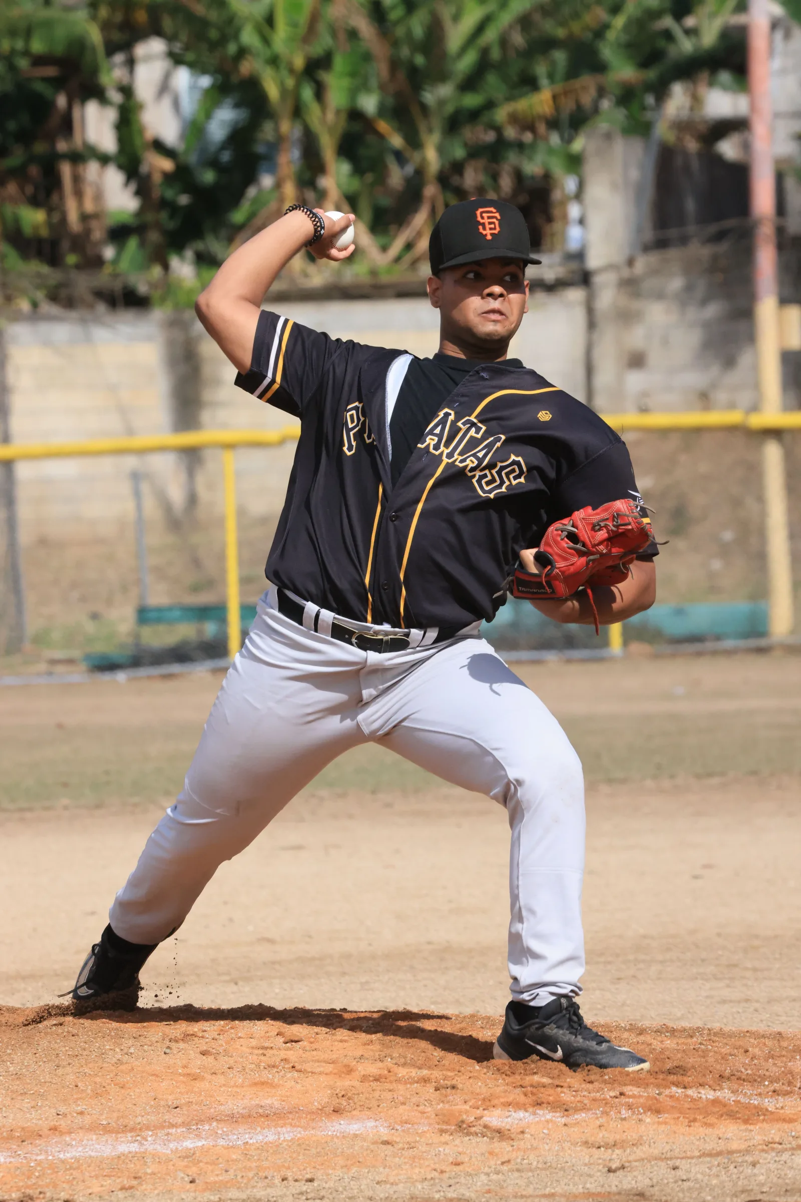Joven jugador de béisbol en acción lanzando en un campo al aire libre durante el día.