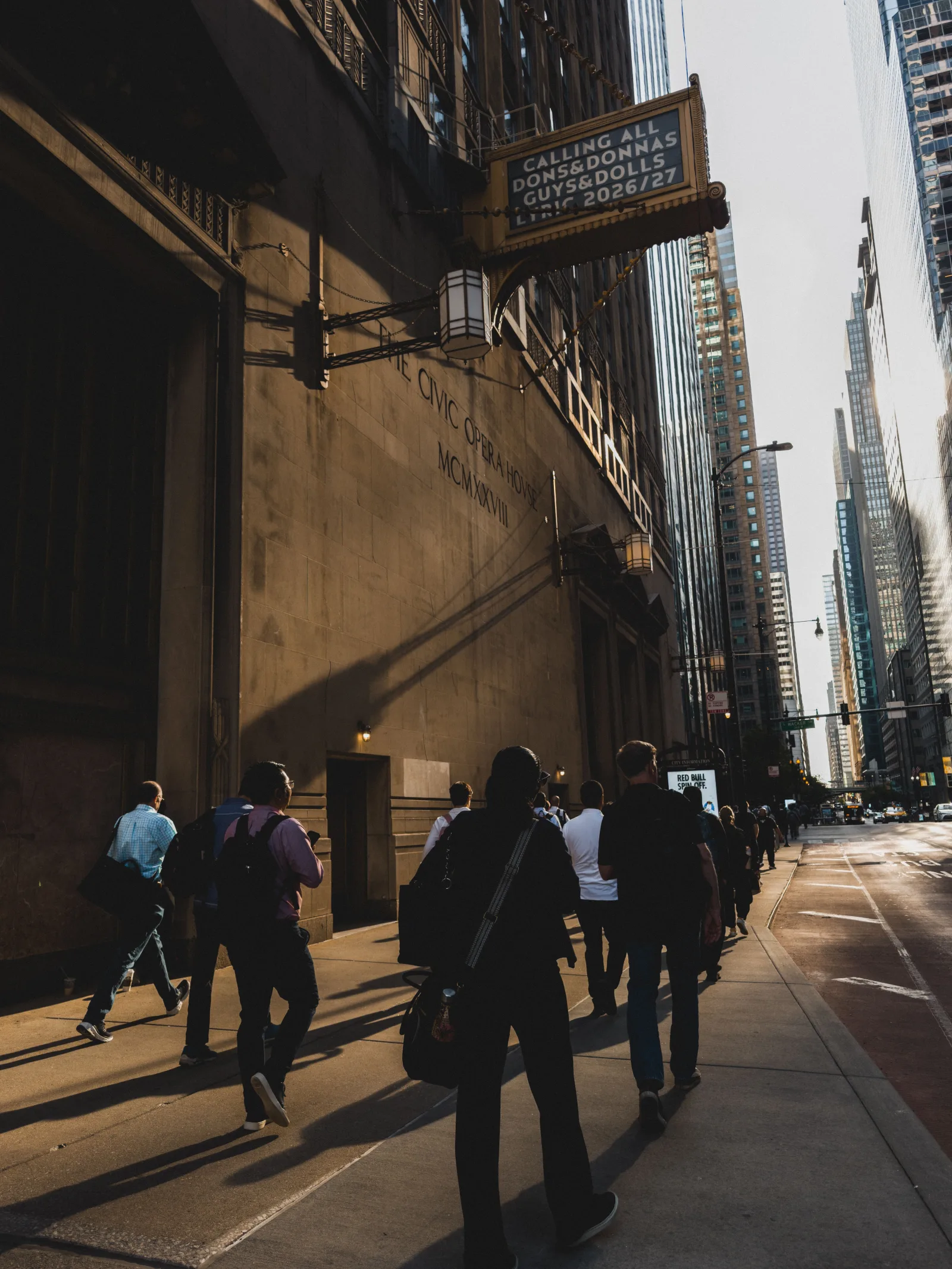 Una animada escena urbana con gente caminando por una calle de Chicago al atardecer, rodeada de rascacielos.