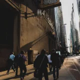 Una animada escena urbana con gente caminando por una calle de Chicago al atardecer, rodeada de rascacielos.