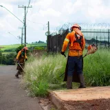 Dos trabajadores en Londrina, Brasil, cortan la hierba del borde de la carretera con desbrozadoras.