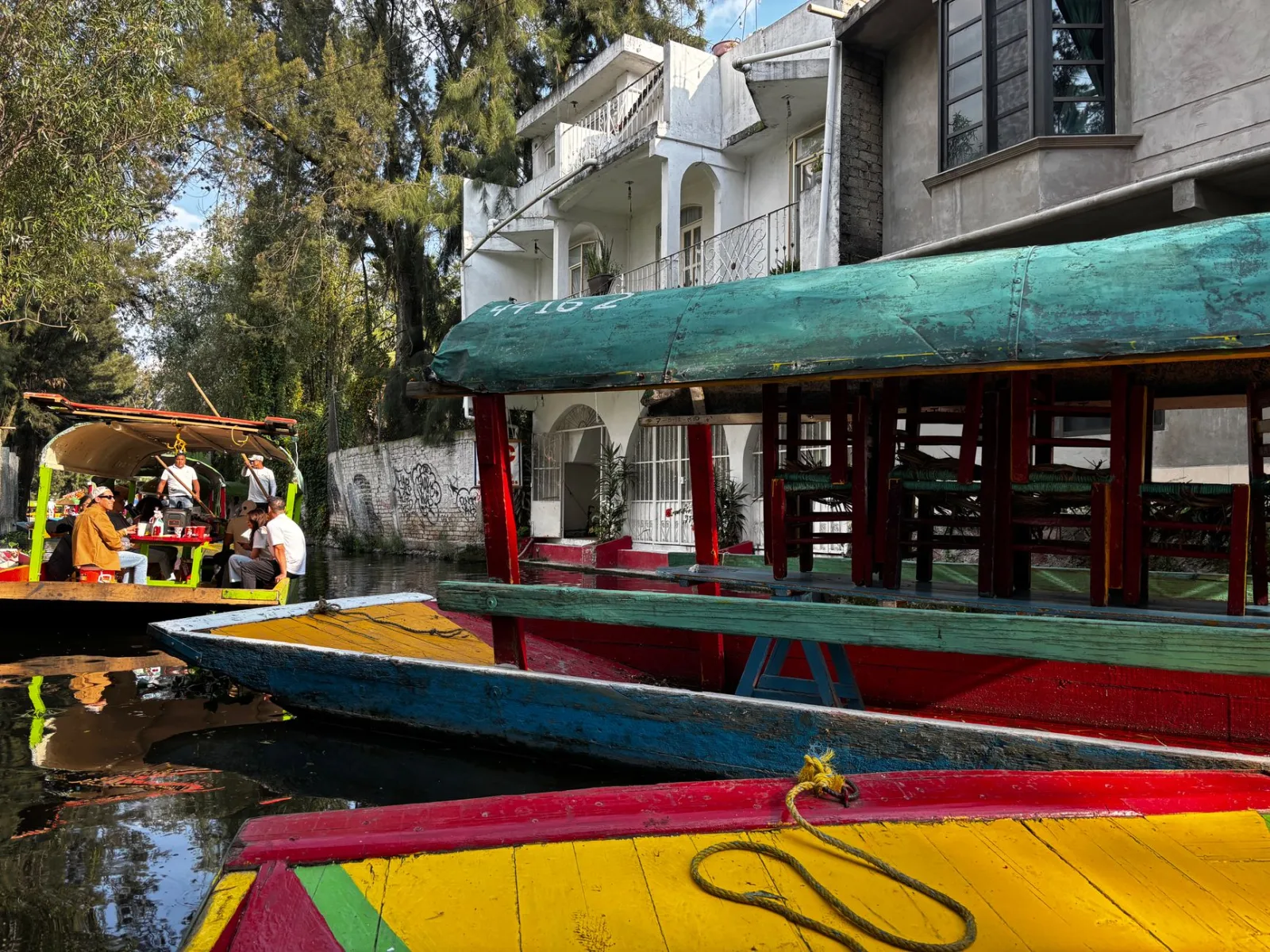Coloridas embarcaciones tradicionales flotando en un canal de Xochimilco, Ciudad de México, durante el día.