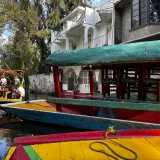 Coloridas embarcaciones tradicionales flotando en un canal de Xochimilco, Ciudad de México, durante el día.