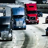Trucks and cars traveling on a congested city highway during the day.