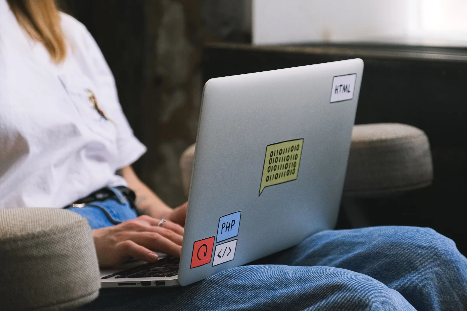 Persona escribiendo en una laptop con pegatinas de código, simbolizando el trabajo remoto y el trabajo freelance.