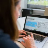 A woman engineer focuses on software analysis using a laptop indoors.