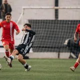 Intensa acción de fútbol mientras los jugadores compiten por el balón en un día soleado.