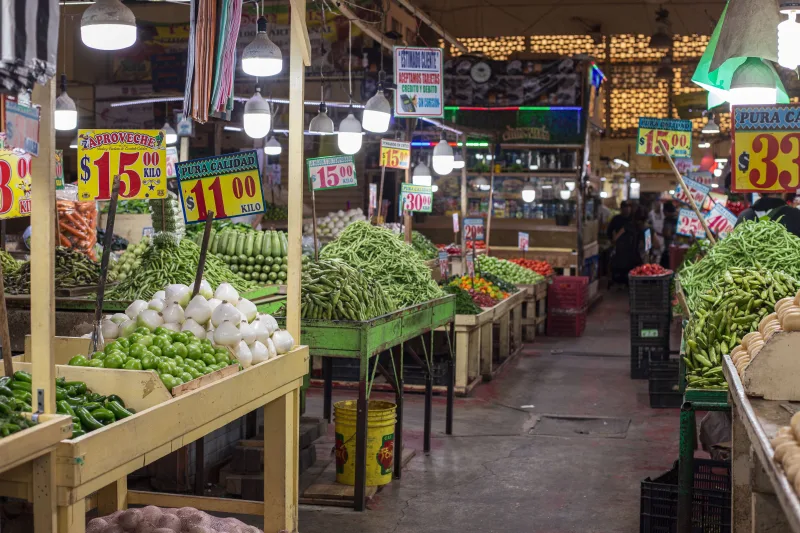 Un colorido y bullicioso mercado interior en la Ciudad de México, con puestos de productos frescos.