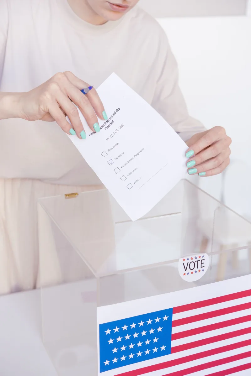 Una persona depositando su voto en una urna transparente durante unas elecciones.