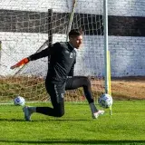 Soccer goalkeeper in action during outdoor practice on a sunny day.