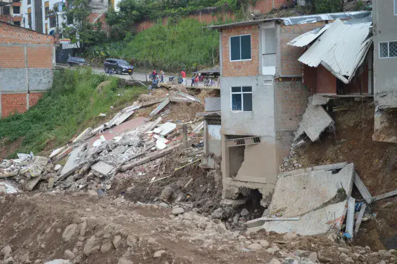 A residential building partially collapsed due to a natural disaster, showcasing severe structural damage.