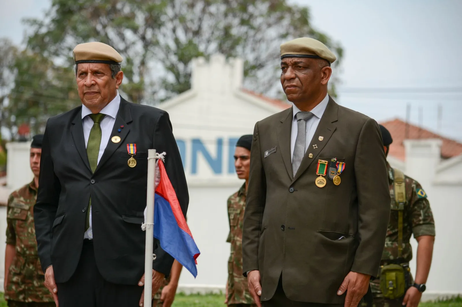 Veteranos condecorados por su servicio permanecen solemnemente en una ceremonia militar al aire libre.