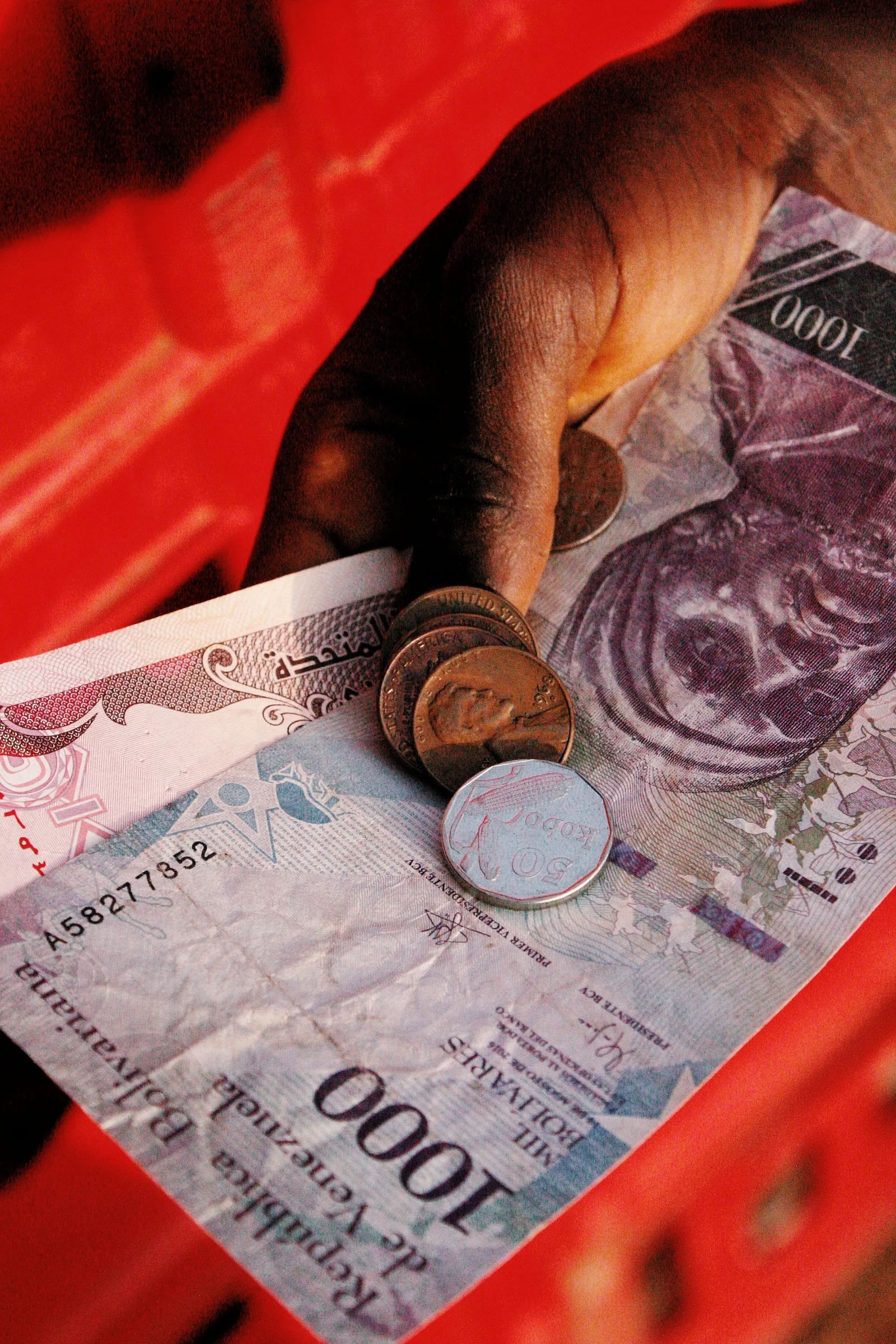 Una vista detallada de una mano sosteniendo la moneda nigeriana, incluyendo un billete de 1000 Naira y monedas.