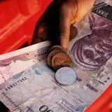 Una vista detallada de una mano sosteniendo la moneda nigeriana, incluyendo un billete de 1000 Naira y monedas.