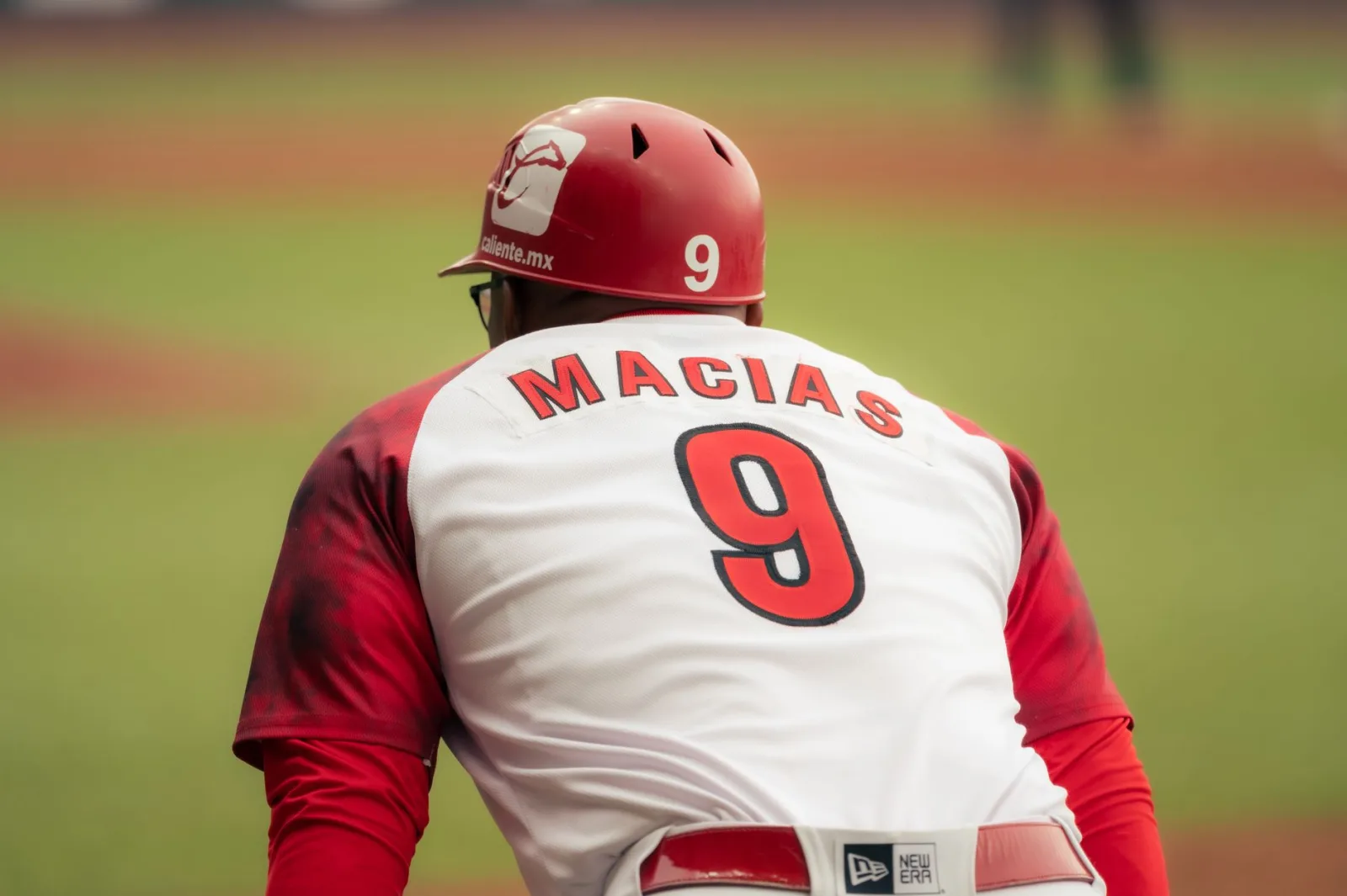 Jugador de béisbol en acción, con una camiseta con el número 9, en el campo.