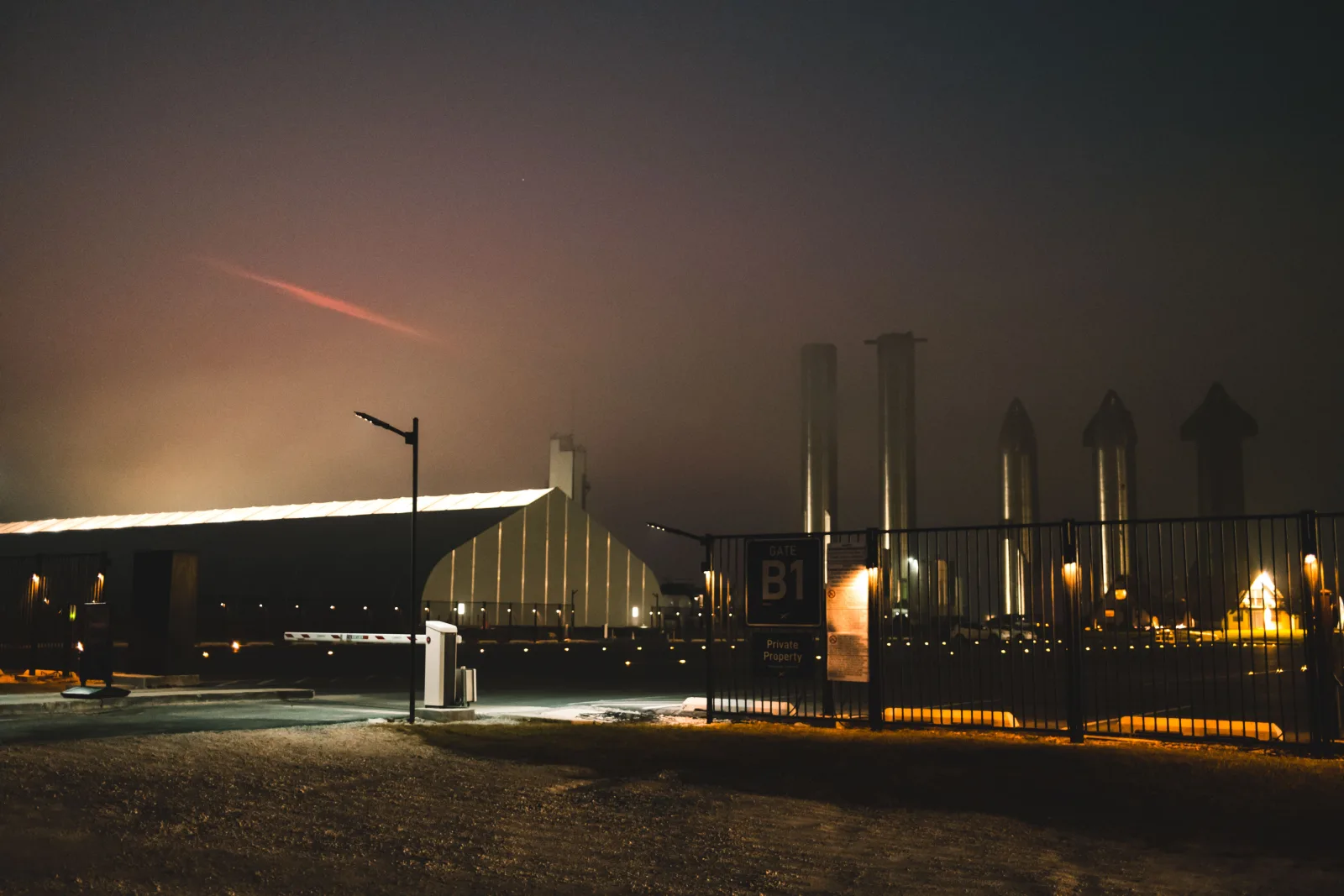 Vista nocturna dramática de la instalación de SpaceX con niebla y luces en Brownsville, Texas.