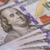 Primer plano detallado de billetes de cien dólares estadounidenses desplegados en abanico, que muestra los detalles de la moneda.