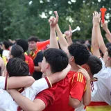 Grupo de aficionados al fútbol entusiastas celebrando una victoria en Madrid, abrazándose y vitoreando al aire libre.