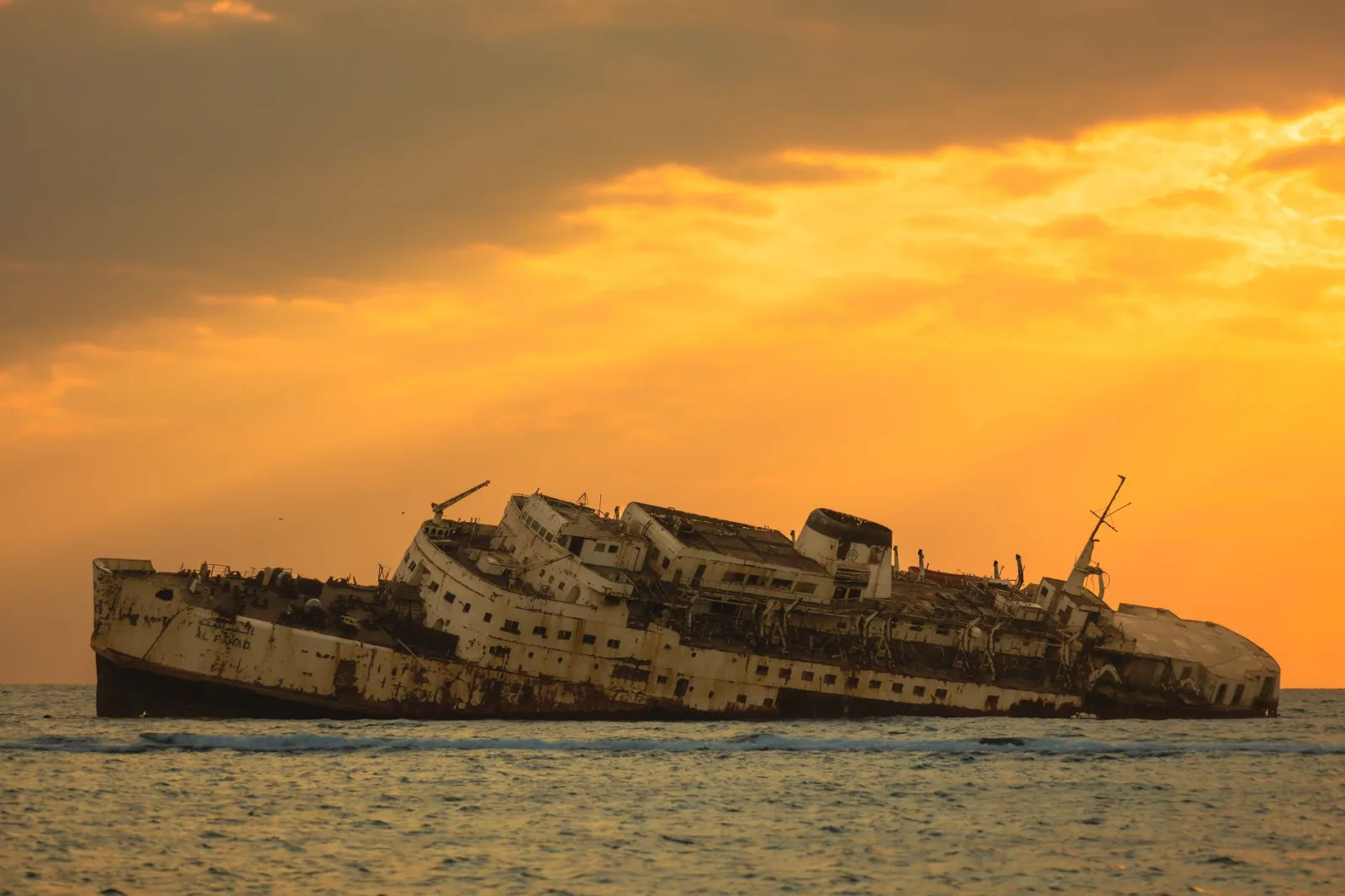 Fotografía de un pecio en descomposición contra un atardecer dorado en las aguas de Jeddah, Arabia Saudita.