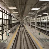 A bustling train station in Cádiz with modern architecture and multiple tracks.