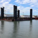 Industrial boats and warehouses at El Puerto de Santa María harbor, depicting a serene maritime scene.