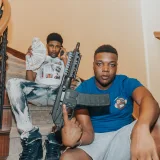 Two young men sitting on a staircase holding cash and a weapon in Las Vegas.