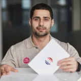 A man with a 'I am a voter' sticker casting his ballot on election day.