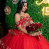 A young woman in a red gown celebrating her quinceañera with roses and tiara.