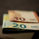 A detailed close-up shot of 10 and 20 euro banknotes placed on a smartphone, representing finance and technology.