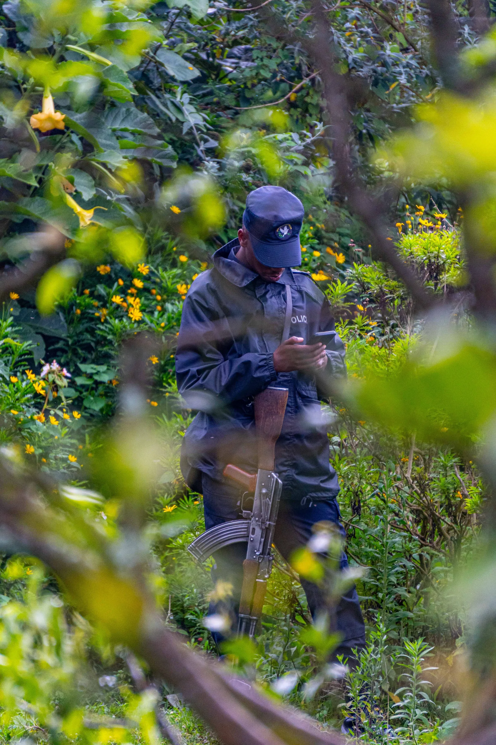 Un oficial de seguridad uniformado de pie en un entorno de vibrante y verde bosque, sosteniendo un arma.